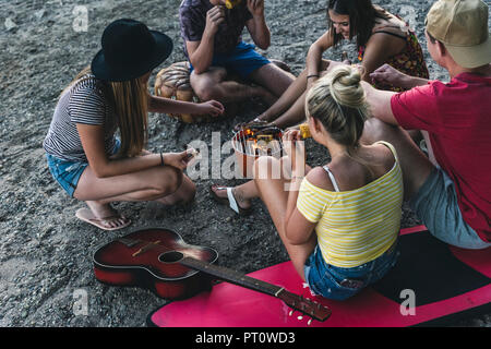 Gruppo di amici seduti insieme a un barbecue Foto Stock