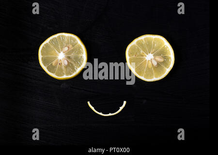 Sorridente volto accattivante da limoni su uno sfondo scuro, il concetto di felicità e di gioia Foto Stock