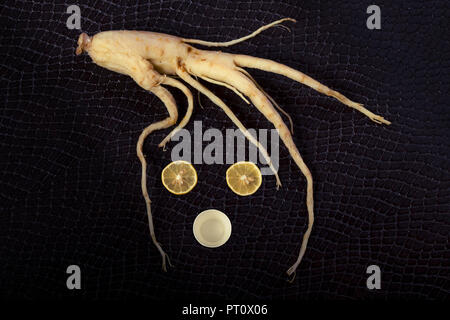 Il ginseng museruola con limoni al posto degli occhi e una tazza di tè in corrispondenza della bocca, immagine di sfondo sulla pelle di serpente Foto Stock