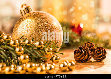 Goldene christbaumkugel mit Tannenzweig, Kerze, Lichter und Deko Foto Stock