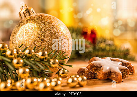 Goldene christbaumkugel mit Tannenzweig, Kerze, Lichter und Deko Foto Stock