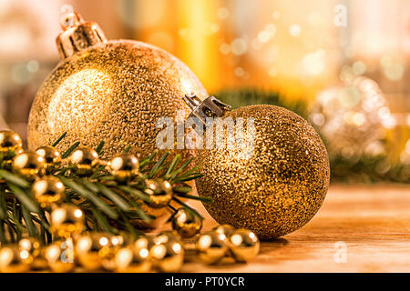 Goldene christbaumkugel mit Tannenzweig, Kerze, Lichter und Deko Foto Stock