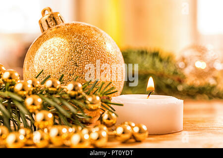 Goldene christbaumkugel mit Tannenzweig, Kerze, Lichter und Deko Foto Stock