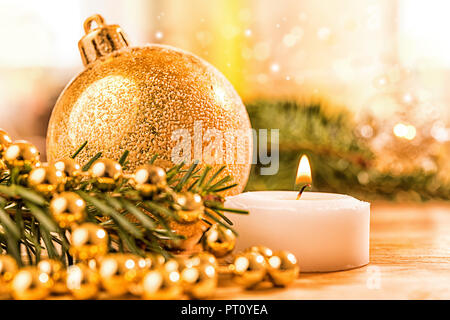 Goldene christbaumkugel mit Tannenzweig, Kerze, Lichter und Deko Foto Stock