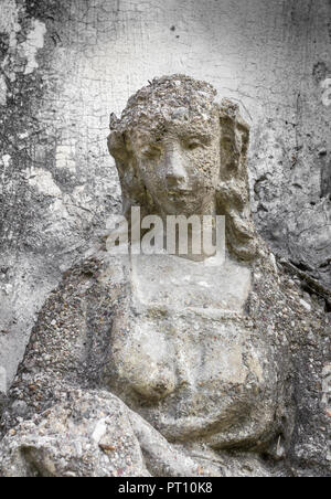 Antica statua di una donna con una espressione triste. Su uno sfondo grigio e parete ruvida. Ideale per i concetti e gli sfondi. Foto Stock