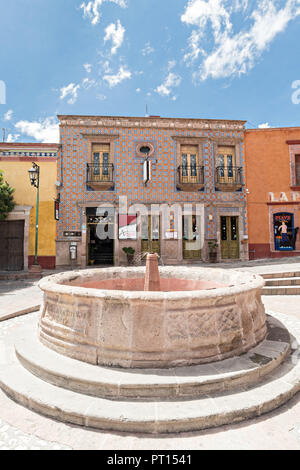 Vista attraverso un'arcata del Bernal fontana pubblica a Saragozza e Hidalgo strade nel bellissimo villaggio coloniale di Bernal, Queretaro, Messico. Bernal è una pittoresca città coloniale noto per la Peña de Bernal, un monolito gigante che domina il piccolo borgo è la terza più alta del pianeta. Foto Stock