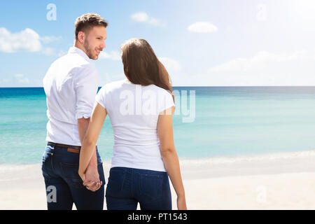 Vista posteriore di una coppia giovane a piedi la spiaggia tropicale Foto Stock