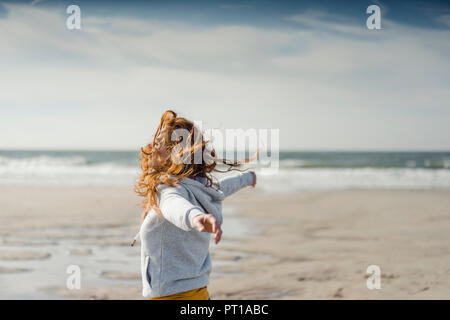 Redheaded donna rilassante sulla spiaggia, con le braccia aperte Foto Stock