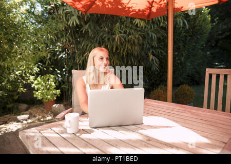 Giovane donna utilizzando laptop in giardino Foto Stock