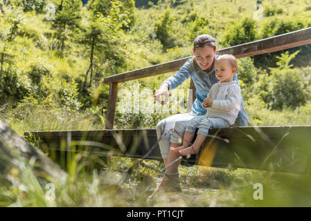 Madre e figlia seduti sul ponte di legno Foto Stock