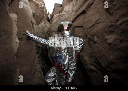 Spaceman esplorando il pianeta anonimi, esaminando canyon Foto Stock