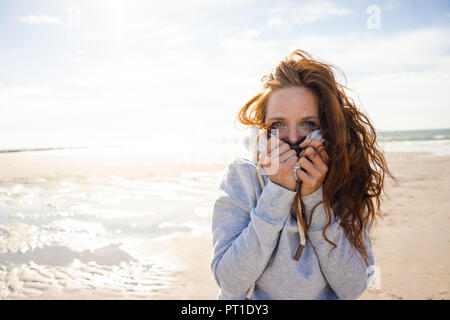 Redheaded donna godendo di aria fresca in spiaggia Foto Stock