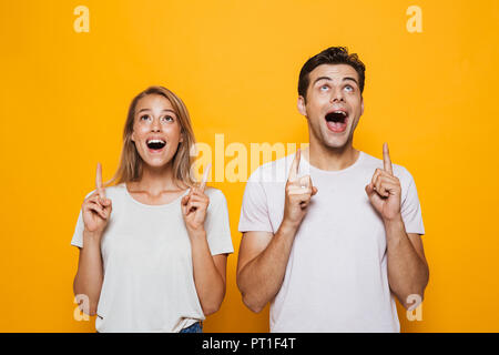 Foto di felice entusiasti giovani amare giovane in piedi isolato sulla parete gialla di puntamento in background. Foto Stock