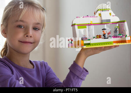 Ritratto di sorridente bambina presentando toy house Foto Stock