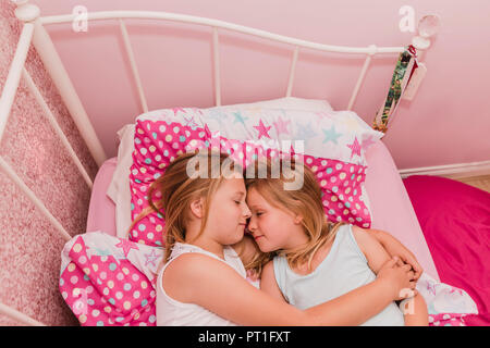 Due piccole sorelle in appoggio sul letto Foto Stock