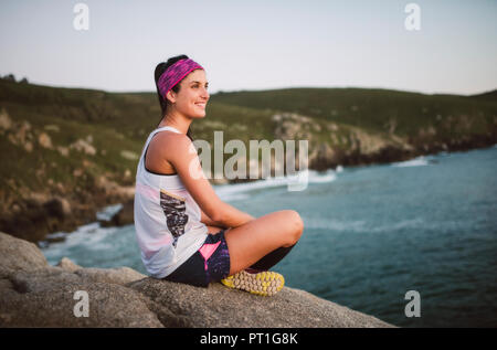 Attività sportive donna seduta sulle rocce di sera Foto Stock