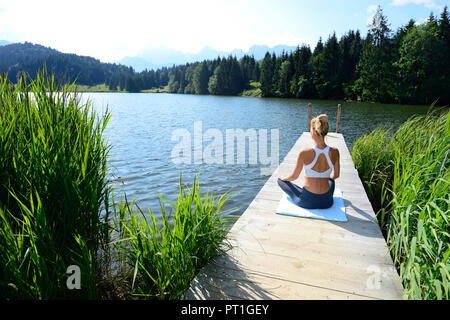 Germania, Mittenwald, vista posteriore della donna a praticare yoga sul molo al lago Foto Stock