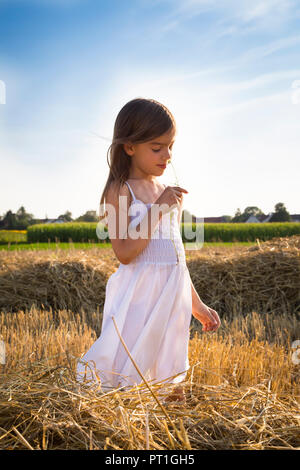 Bambina in piedi nel campo havested odore di fiore Foto Stock