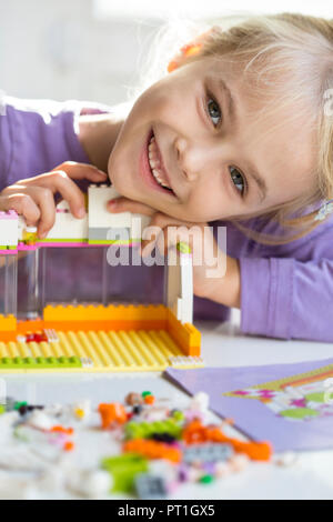 Ritratto di felice bambina gioca con mattoni da costruzione Foto Stock