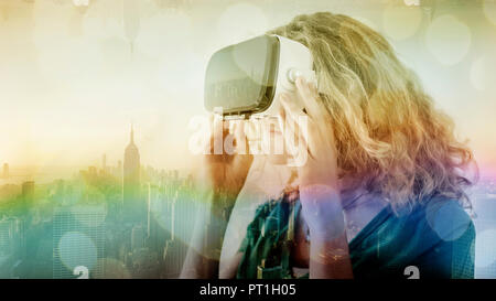 Stati Uniti d'America, New York City, giovane donna utilizzando occhiali per realtà virtuale, composito Foto Stock