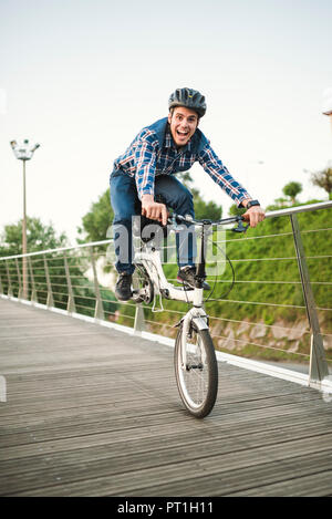 Giovane uomo fare trucchi con una bicicletta pieghevole Foto Stock