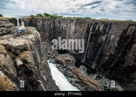 Lo Zimbabwe, donna guardando Victoria Falls Foto Stock