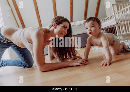 La madre e il bambino figlio di giocare e strisciando sul piano Foto Stock