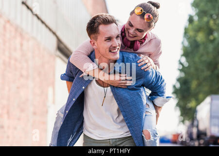 Giovane uomo dando ragazza piggyback ride Foto Stock