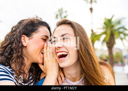 Due felici amici femmina whispering e ridere Foto Stock