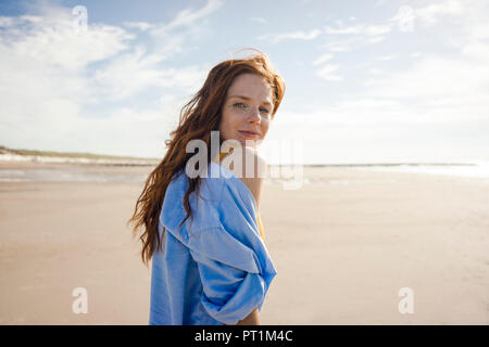 Donna sulla spiaggia, guardando sopra la spalla Foto Stock