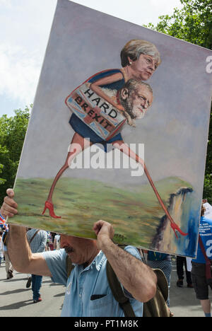 Uomo che porta un dipinto sul suo retro di stilizzata Teresa può trasportare Jeremy Corby camminando su di una scogliera con didascalia "Hard Brexit' Foto Stock