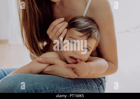 Madre coccole e giocare con il suo bambino figlio Foto Stock