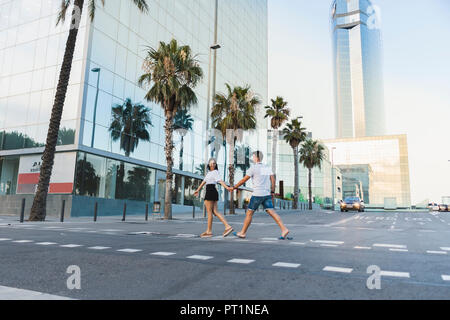 Coppia giovane attraversando le strade della città, tenendo le mani Foto Stock