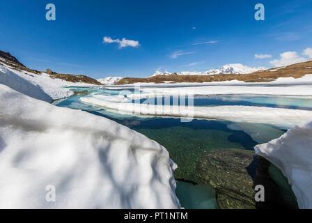 Le acque cristalline del Lago Emet circondato da neve durante il disgelo, Madesimo, Val Chiavenna, Valle Spluga, Valtellina, Lombardia, Italia, Europa Foto Stock