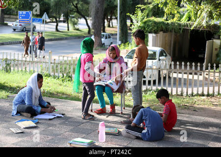 Islamabad, Pakistan. 5 Ottobre, 2018. Un insegnante controlla il lavoro dei suoi studenti di una scuola di fortuna istituito in un parco pubblico a Islamabad, la capitale del Pakistan, il 5 ottobre, 2018. Il mondo degli insegnanti di giorno è osservato su 5 Ottobre. Credito: Ahmad Kamal/Xinhua/Alamy Live News Foto Stock