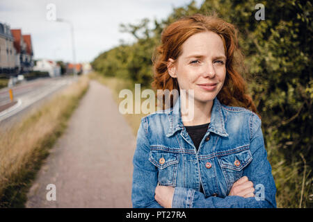 Redheaded donna con le braccia incrociate, ritratto Foto Stock