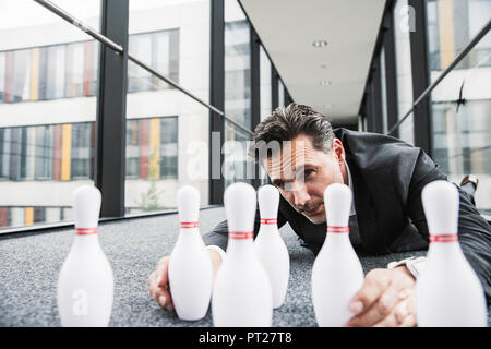 Diligente manager sdraiato sul pavimento in ufficio di passaggio dei perni di regolazione Foto Stock