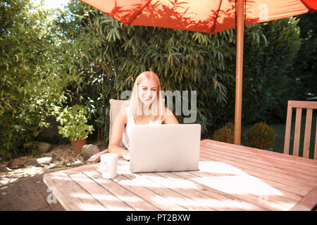 Giovane donna utilizzando laptop in giardino Foto Stock
