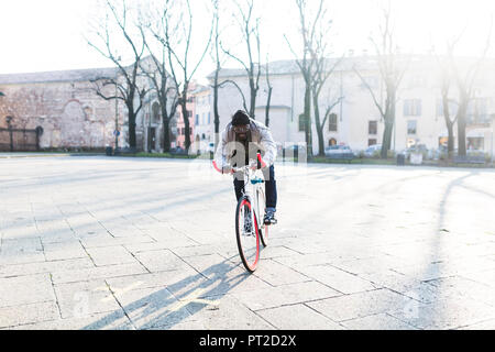 Giovane uomo Bicicletta Equitazione su piazza urbana Foto Stock