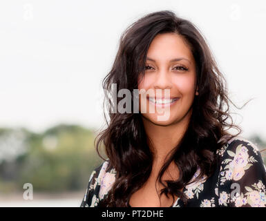 Ritratto di una bella donna ispanica felice e sorridente con sfondo semplice Foto Stock