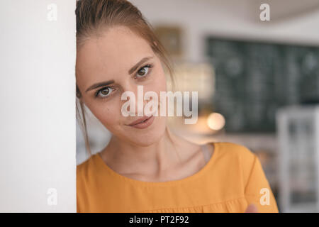 Giovane donna in piedi in cafe, ritratto Foto Stock