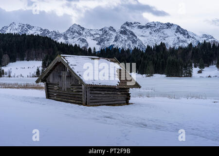 L'Europa, in Germania, in Baviera, il fienile di fronte al Geroldsee congelati e sulle montagne del Karwendel Foto Stock