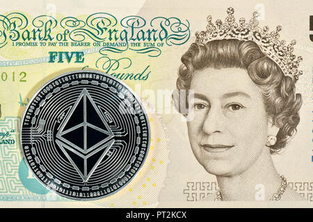 Immagine simbolica di valuta digitale, argento fisico coin Ethereum sulla banconota 5 Inglese Sterline Foto Stock