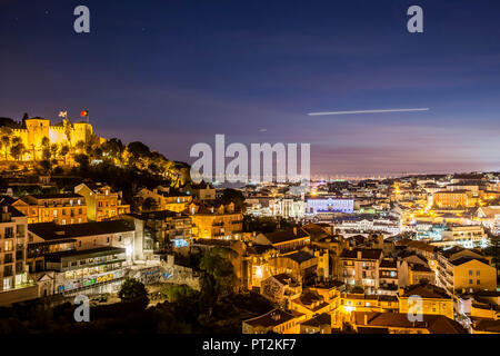 Notte su Lisbona Sao Jorge fortezza e centro illuminato, vista dal Miradouro da Graca Foto Stock