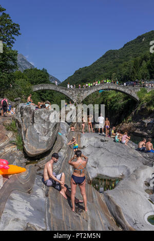 La balneazione nel fiume Verzasca nella parte anteriore del ponte dei Salti, nei pressi di Lavertezzo, Valle Verzasca, Ticino, Svizzera Foto Stock