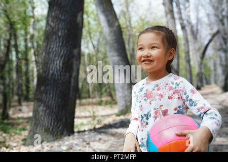 Bambina giocano con una palla in un parco Foto Stock