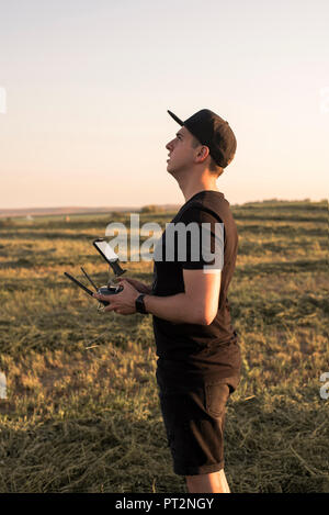 Uomo con telecomando per un drone in un campo Foto Stock