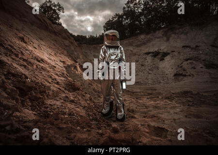Spaceman esplorando il pianeta anonimi, tenendo in mano la torcia Foto Stock