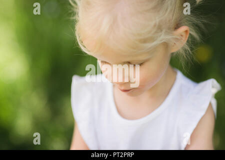 La bionda bambina guardando verso il basso Foto Stock