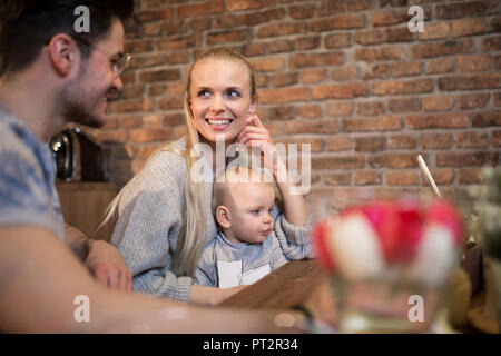 Felice giovani genitori di trascorrere del tempo in cucina a casa con la loro bambina Foto Stock